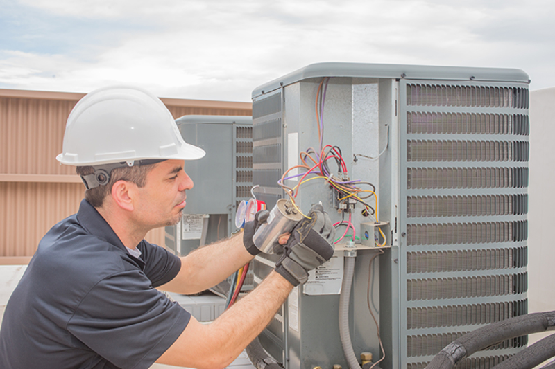 5 Reasons to Let a Commercial HVAC Professional Handle Repairs. A handyman doing repairs on an HVAC system.