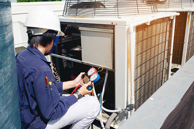 7 Ways to Prepare Your Commercial HVAC System for Winter. Photo of a professional performing maintenance on an HVAC Unit.